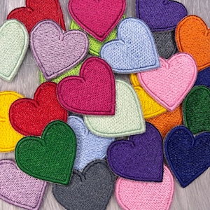 Peut inclure: Une collection de patchs en forme de cœur en feutre de différentes couleurs, notamment rouge, rose, bleu, vert, jaune et violet. Les cœurs sont de tailles et de formes différentes et sont disposés de manière aléatoire.