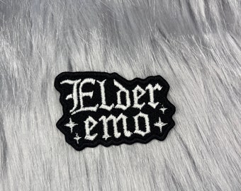 May include: Black embroidered patch with white lettering that reads "Elder emo" with two white stars on either side of the text.