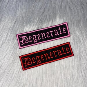 May include: Two embroidered patches with the word "Degenerate". One patch has a black background with pink border and lettering. The other patch has a black background with a red border and lettering. Both patches are rectangular.