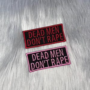 May include: Two rectangular embroidered patches with black backgrounds and stitched borders. The top patch features red text reading DEAD MEN DON'T RAPE. The bottom patch features pink text reading DEAD MEN DON'T RAPE in the same font style.