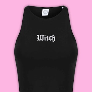 May include: A black sleeveless crop top featuring a high neckline and the word Witch printed in white gothic-style lettering across the centre chest. A small white circular tag with the letters SF is visible at the inside of the neckline.