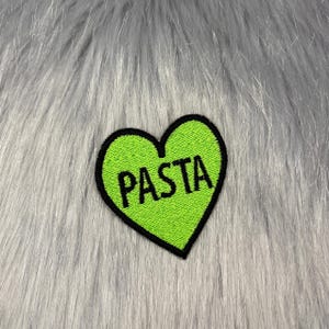May include: Green heart-shaped patch with black outline and the word "PASTA" embroidered in black.
