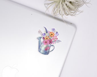 May include: A blue watering can filled with a bouquet of colorful flowers, including pink, orange, yellow, and purple flowers. The flowers are arranged in a whimsical way, with some spilling out of the can.