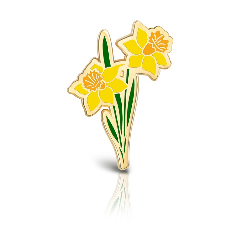 May include: A gold-tone enamel pin featuring two yellow daffodils with orange centers and green leaves.