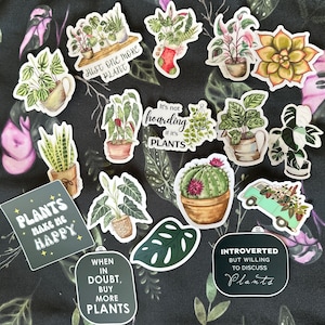 May include: A collection of 12 plant-themed stickers with various designs and sayings. The stickers feature illustrations of plants, cacti, and a van filled with plants. Some of the sayings include "Just one more plant", "It's not hoarding if it's plants", "Plants make me happy", "When in doubt, buy more plants", and "Introverted but willing to discuss plants".