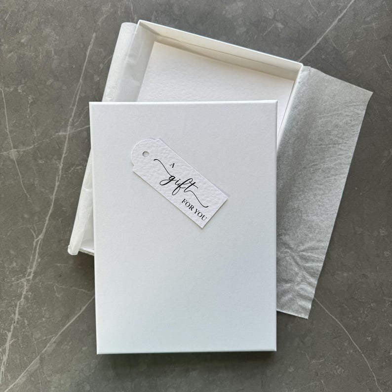 May include: A white gift box with a white tag that says "a gift for you" in black script.