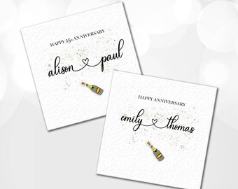 May include: Two white cards with gold glitter and a champagne bottle illustration. The first card says "Happy 25th Anniversary alison & paul". The second card says "Happy Anniversary emily & thomas".