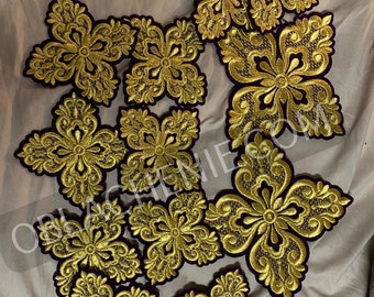 May include: A set of 11 gold embroidered crosses with intricate floral designs on a purple velvet backing.