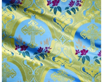 May include: Blue and gold fabric with a repeating pattern of crosses and floral designs. The fabric has a subtle sheen and a luxurious feel.