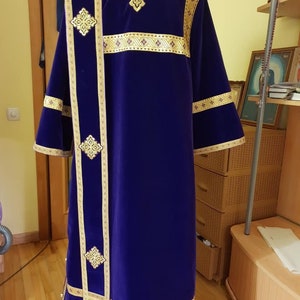 May include: A purple velvet robe with gold embroidery. The robe has a large cross on the back and smaller crosses on the sleeves. The robe is trimmed with gold braid.