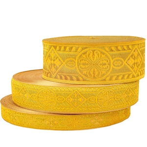 Puede incluir: Tres rollos de ribete amarillo con un intrincado patrón floral. El ribete está hecho de una tela tejida y tiene una textura ligeramente en relieve.