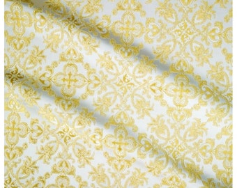 Pode incluir: Tecido branco com um padrão dourado, intrincado e repetitivo de cruzes estilizadas e desenhos florais.