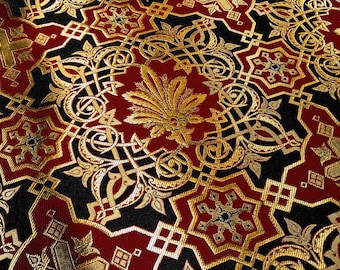 Puede incluir: Primer plano de una tela roja y negra con un patrón dorado. El patrón es intrincado y presenta un diseño repetitivo de estrellas, cuadrados y espirales.