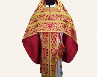 May include: A red and gold liturgical vestment set featuring intricate brocade patterns with floral motifs. The ensemble includes a wide, cape-like upper garment with a high collar and a matching long, rectangular panel with gold fringe trim.