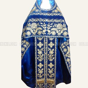 May include: A blue velvet liturgical vestment with gold embroidery featuring floral designs and a decorative border. The vestment has a matching stole with a fringe.
