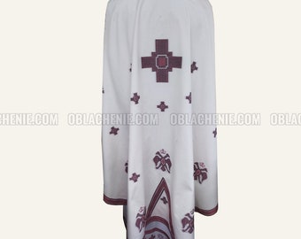 May include: White liturgical vestment with a large red cross and smaller red floral designs. The vestment has a high collar and is made of a lightweight fabric.