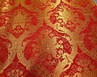 May include: Red fabric with a gold floral pattern. The pattern features stylized flowers, leaves, and crowns.