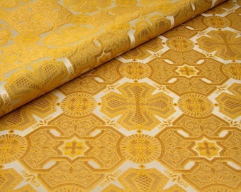 May include: Gold fabric with a repeating pattern of crosses and geometric shapes. The fabric has a subtle sheen and a luxurious feel.