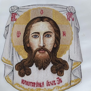 Könnte beinhalten: Gestickte Ikone von Jesus Christus mit einem goldenen Heiligenschein und dem Text "IC XC NIKA" in Rot und Gold. Der Text "Не Рукотворный Образ" ist unten in Rot und Gold gestickt.