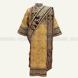 Pode incluir: Uma veste litúrgica dourada com uma faixa bordô e bordados intrincados. A faixa apresenta o texto cirílico "СВТ" em fio dourado.