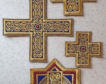 May include: Three embroidered crosses with intricate gold designs on a blue background. The crosses have red jewels in the center.