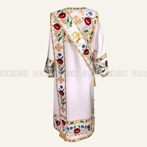 May include: White liturgical robe with gold and floral embroidery. The robe features a red poppy design and the text "C.T.L." on the sash.