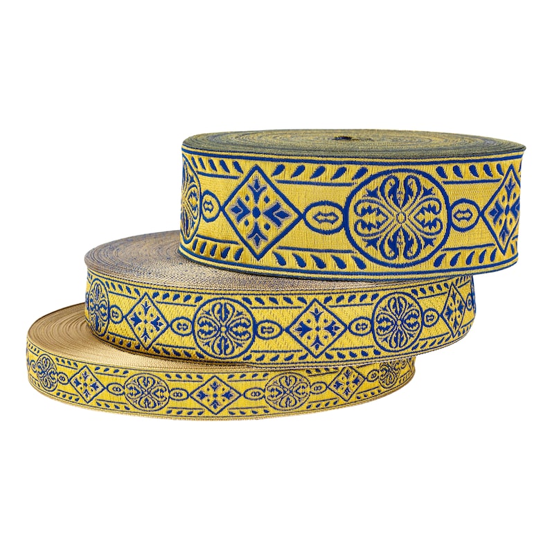 May include: Three rolls of gold and blue patterned trim with a geometric design. The trim is woven with a repeating pattern of blue squares and circles on a gold background.