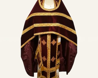 May include: A deep burgundy velvet liturgical vestment set featuring intricate gold embroidery and trim. The ensemble includes a wide cape with horizontal gold bands and a matching long garment adorned with embroidered cross motifs and gold fringe.