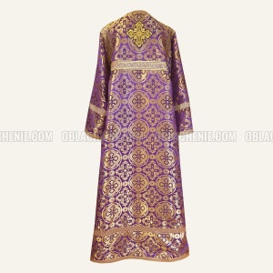 May include: A purple liturgical vestment with gold embroidery and a cross design. The vestment has a long, flowing shape and is decorated with intricate patterns.