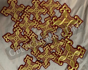 May include: A group of 13 gold embroidered crosses on a red velvet background. The crosses are intricately designed with a floral pattern.
