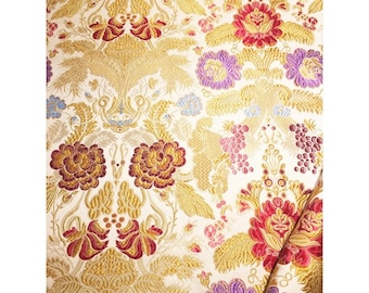 Puede incluir: Tela blanca con un patrón floral dorado, rojo y morado. La tela tiene un aspecto texturizado y tejido.