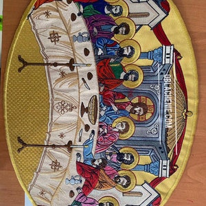 Puede incluir: Una representación bordada detallada de la Última Cena, con Jesús y sus discípulos reunidos alrededor de una mesa. La escena se desarrolla sobre un fondo dorado con detalles intrincados y un edificio de iglesia en el fondo.
