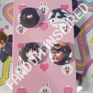 May include: Pink tin with a white bunny design and four round buttons featuring anime characters. The buttons are attached to the tin with a pink heart design.