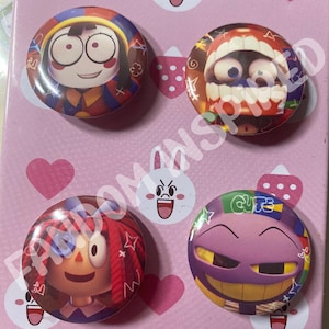 May include: Four colorful round buttons with cartoon characters from the game 'Poppy Playtime'. The characters are Poppy, Huggy Wuggy, Kissy Missy, and Mommy Long Legs. Each button has a different color scheme and features a different character.
