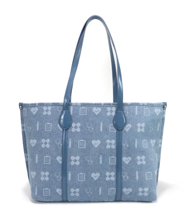 Puede incluir: Una bolsa de mano de color azul claro con un patr&oacute;n de corazones, vendas, estetoscopios y gr&aacute;ficos m&eacute;dicos. La bolsa tiene dos asas largas y un forro de color azul claro.