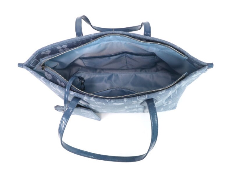 Puede incluir: Un bolso tote azul claro con un patr&oacute;n blanco. El bolso tiene una cremallera y dos asas superiores. El bolso est&aacute; abierto y el interior est&aacute; forrado con un tejido azul claro. Hay un peque&ntilde;o bolsillo con cremallera en el interior del bolso.