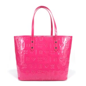 Puede incluir: Un bolso tote de color rosa brillante con un acabado brillante. El bolso tiene un patr&oacute;n de corazones, cruces y otros s&iacute;mbolos en relieve en la superficie.