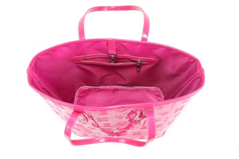 Puede incluir: Un bolso tote de charol rosa con un bolsillo con cremallera y un peque&ntilde;o bolsillo interior. El bolso tiene un patr&oacute;n de monograma.