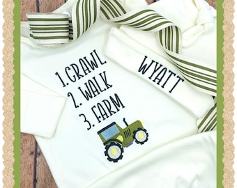 May include: A white baby onesie with the text "1. Crawl 2. Walk 3. Farm" and a green tractor graphic. A white hat with the name "Wyatt" embroidered on it is included.