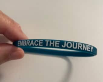 Embrace the Journey stretchy durable silicone wristband measures 1/4" x 8". Buyers have options to add 2 thin or 1 wide band