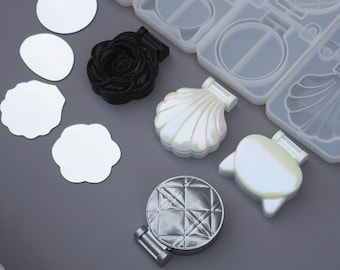 May include: A set of six compact mirror molds, including a rose, a seashell, a cat, and three round shapes. The molds are made of clear silicone and are designed to create custom compact mirrors.