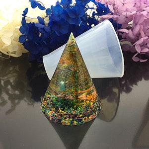 May include: A clear cone-shaped silicone mold for resin casting. The mold is shown with a finished resin casting inside, featuring a colorful, abstract design.