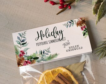 May include: A clear plastic bag filled with a holiday potpourri simmering kit. The kit includes dried orange slices, cinnamon sticks, bay leaves, and star anise. The bag has a white label with the text "Holiday Potpourri Simmering Kit" and "From Helen Griswold".