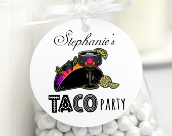 May include: White round favor tag with black text that reads "Stephanie's Taco Party". The tag features a black and colorful illustration of a taco with a margarita glass on top.