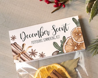 May include: A clear plastic bag filled with dried orange slices, cinnamon sticks, and other spices. The bag has a white label that says "December Scent Potpourri Simmering Kit".