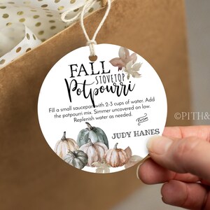 May include: A white round gift tag with a watercolor illustration of pumpkins and fall leaves. The text on the tag reads "Fall Stovetop Potpourri" and includes instructions for using the potpourri. The tag also includes the text "From Judy Hanes".