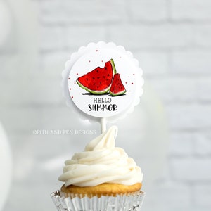 May include: A white cupcake with vanilla frosting topped with a round, white cupcake topper featuring a red watermelon illustration and the text "Hello Summer".