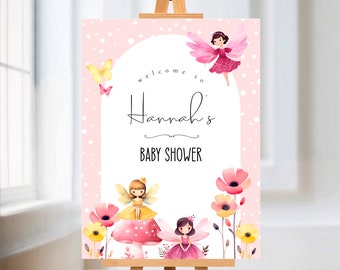 May include: Pink and white baby shower welcome sign with a white arch and the text "Welcome to Hannah's Baby Shower". The sign features three fairies with pink and yellow wings, flowers, and butterflies.