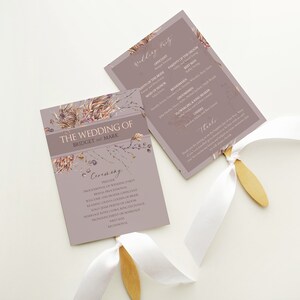 Peut inclure: Un éventail de programme de cérémonie de mariage avec un motif floral dans les tons bruns, roses et violets. L'éventail porte le texte "The Wedding of Bridget and Mark" et liste l'ordre de la cérémonie.