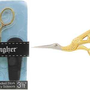 May include: Gold-handled stork embroidery scissors, 3.5 inches long, with a gold finish and silver blades. The scissors are in a clear plastic package with the brand name "gingher" on a black label.